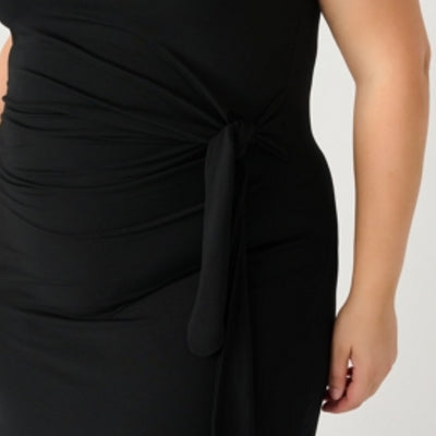 Curvy woman wearing a black dress featuring a flattering knotted detail at the waist 