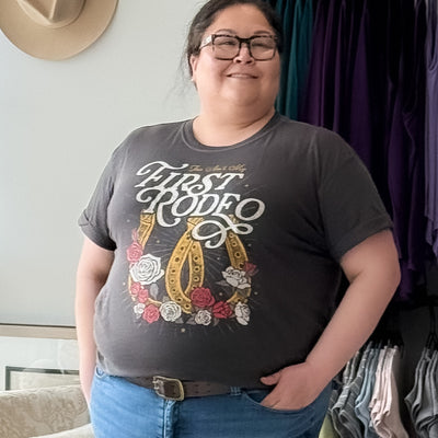 Plus size woman wearing the girl dangerous bit my first rodeo graphic tee with cuffed sleeves and distressed feel