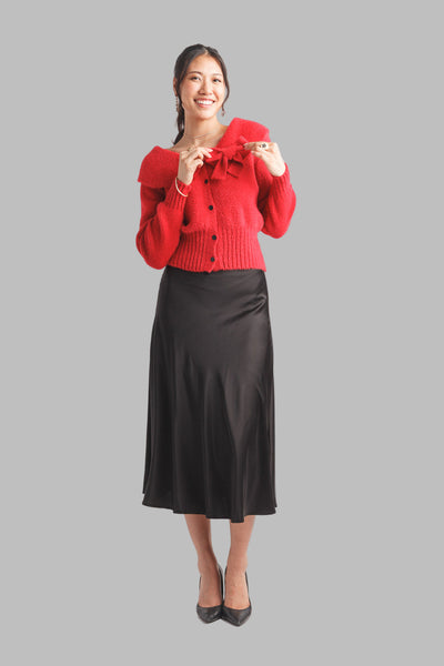 Woman wearing a cute and comfortable boat neck red cardigan with a bow and black buttons