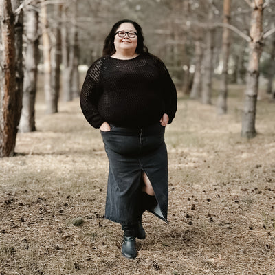 Curvy plus size woman wearing a cute comfortable and trendy black denim midi skirt with a front slit 