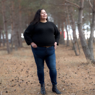 Curvy woman wearing a black soft and comfortable knit sweater with eyelet detailing.  