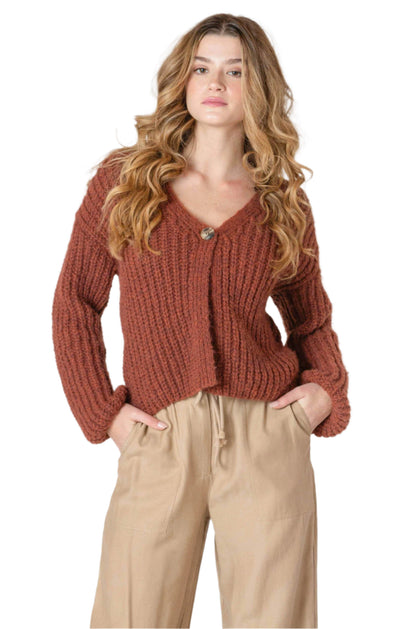 Woman wearing a cute and comfortable rust-colored knitted cardigan with a single button 